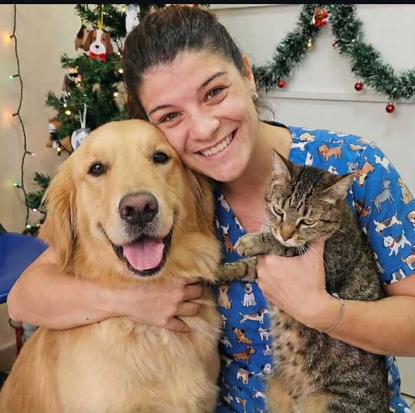 Jésica abrazando a un golden retriever y un gato durante una consulta